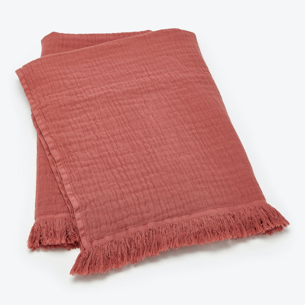 Terracotta blanket with fringed ends, perfect for cozy home decor.