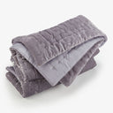 Folded weighted blanket with soft, velvety texture and decorative stitching patterns.