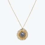 Gold necklace with a deep blue or grey sapphire pendant.