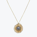 Gold necklace with a deep blue or grey sapphire pendant.
