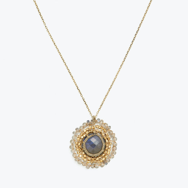 Gold necklace with a deep blue or grey sapphire pendant.
