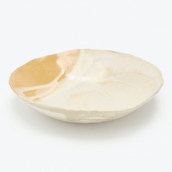 Handmade ceramic plate with irregular edge and textured glaze finish.
