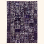Rectangular area rug with distressed patchwork design in purple and grey.
