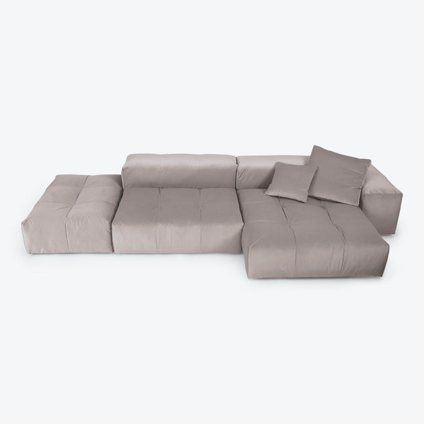 Contemporary and minimalist light gray sectional sofa with tufted cushions.