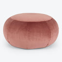 Round, blush-pink pouf with plush velvet texture and stitched segments.