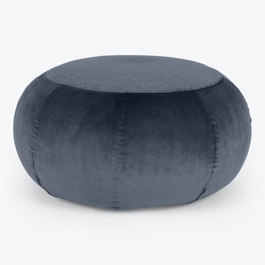 Dark gray velvet pouf with plush cushioned appearance and stitched seams