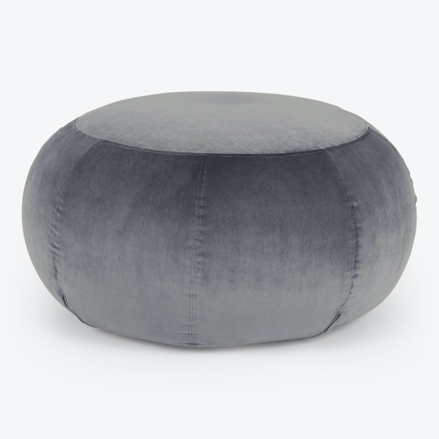 Grey velvet upholstered round pouf with visible stitching for seating