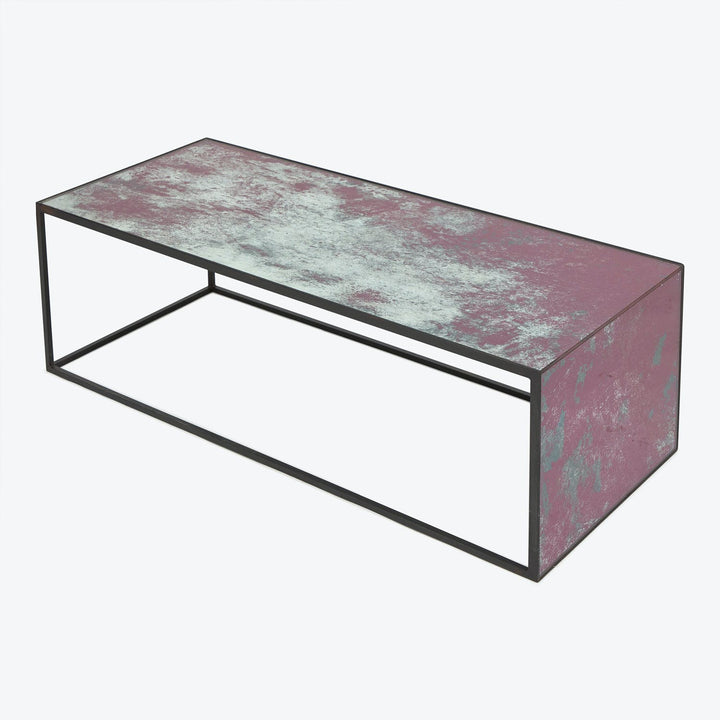 Minimalist coffee table with distressed pink finish and metal frame.