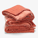 Neatly folded coral quilt with plush texture and stitched detailing.