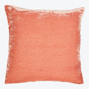 Square coral pillow with textured velvet-like surface on white background.