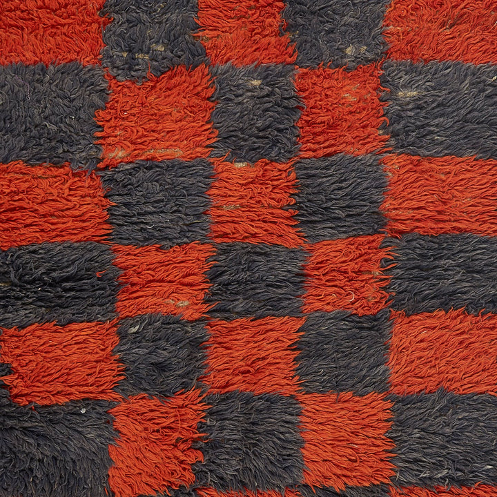 Close-up of fuzzy red and black checkerboard pattern, resembling shaggy carpet.