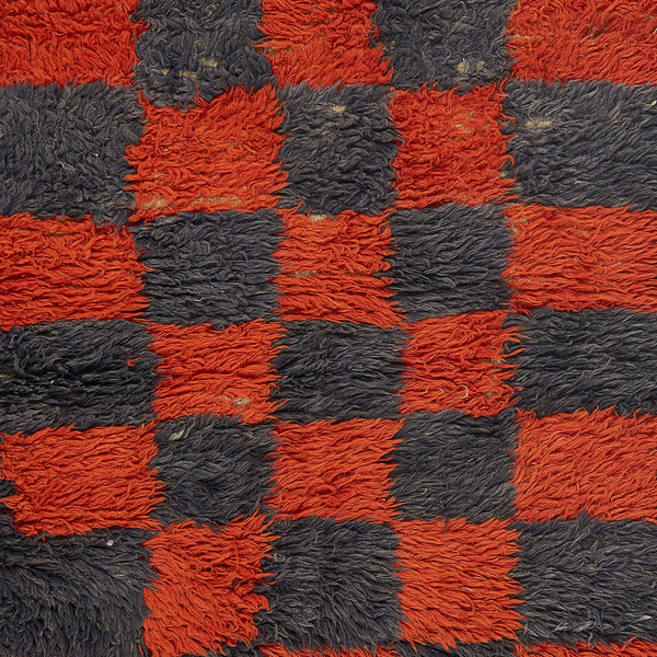 Close-up of fuzzy red and black checkerboard pattern, resembling shaggy carpet.