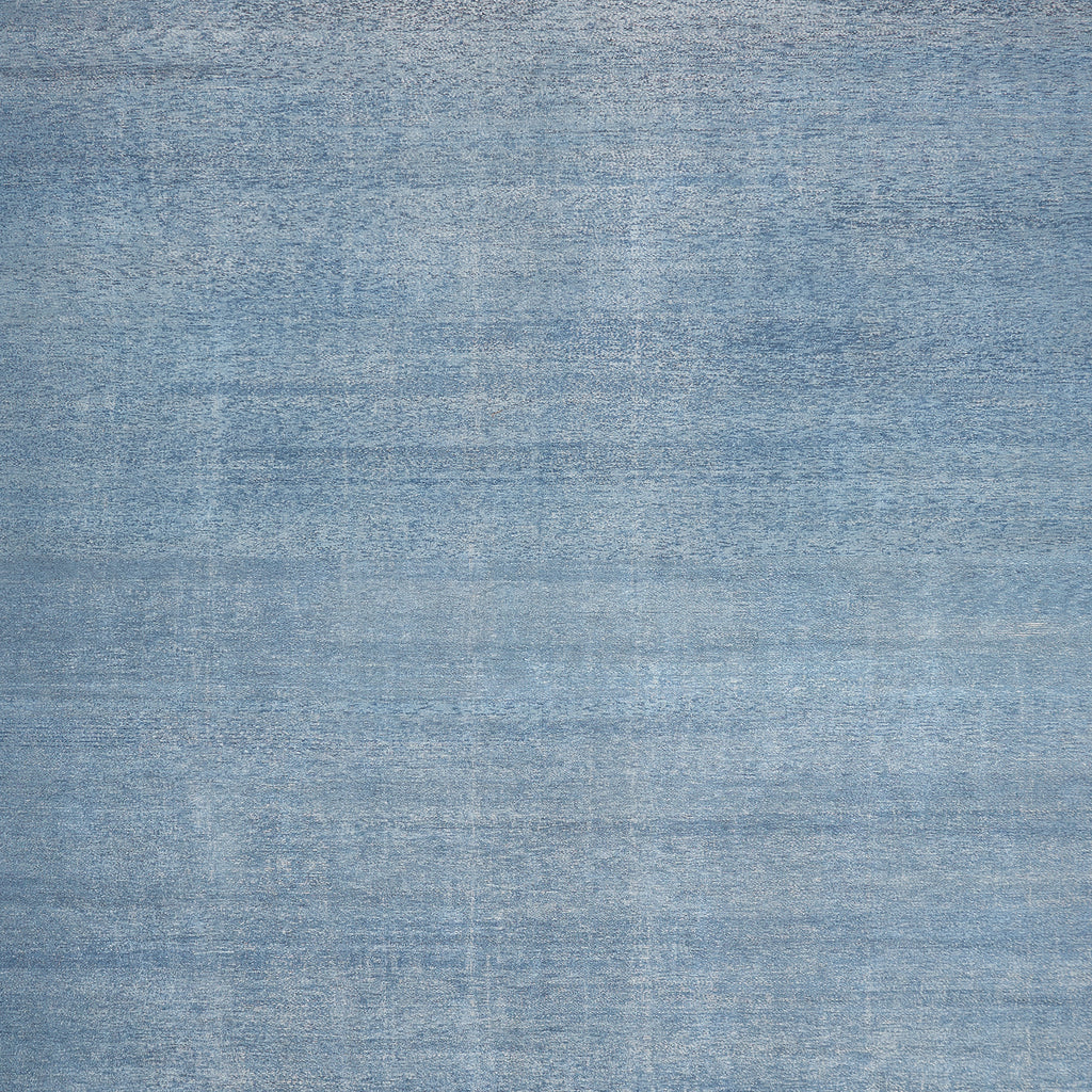 Close-up photograph of blue denim fabric with white threading pattern.