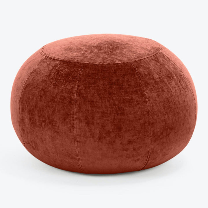 A burnt orange velvet pouf with elegant symmetrical design.