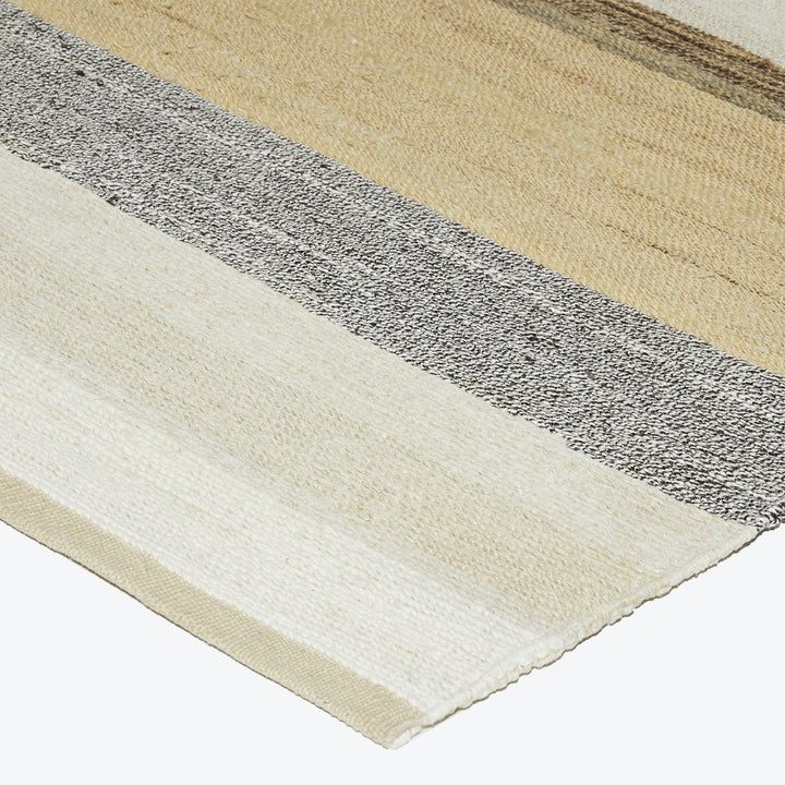 Diagonal textile sample with beige, black and white, and cream stripes.