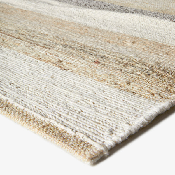 Close-up of a woven rug with horizontal beige and gray stripes.