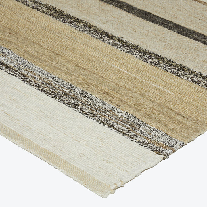 Neutral-toned striped rug with rough and frayed edges for casual style.