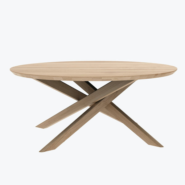 Modern wooden table with a round natural top and X-shaped base.