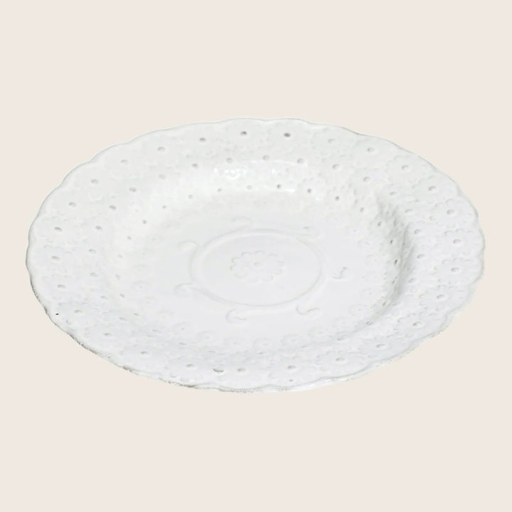 Ornate white ceramic plate with embossed floral design and scalloped edge