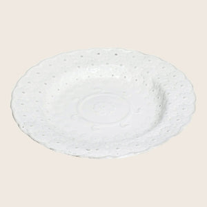 Ornate white ceramic plate with embossed floral design and scalloped edge