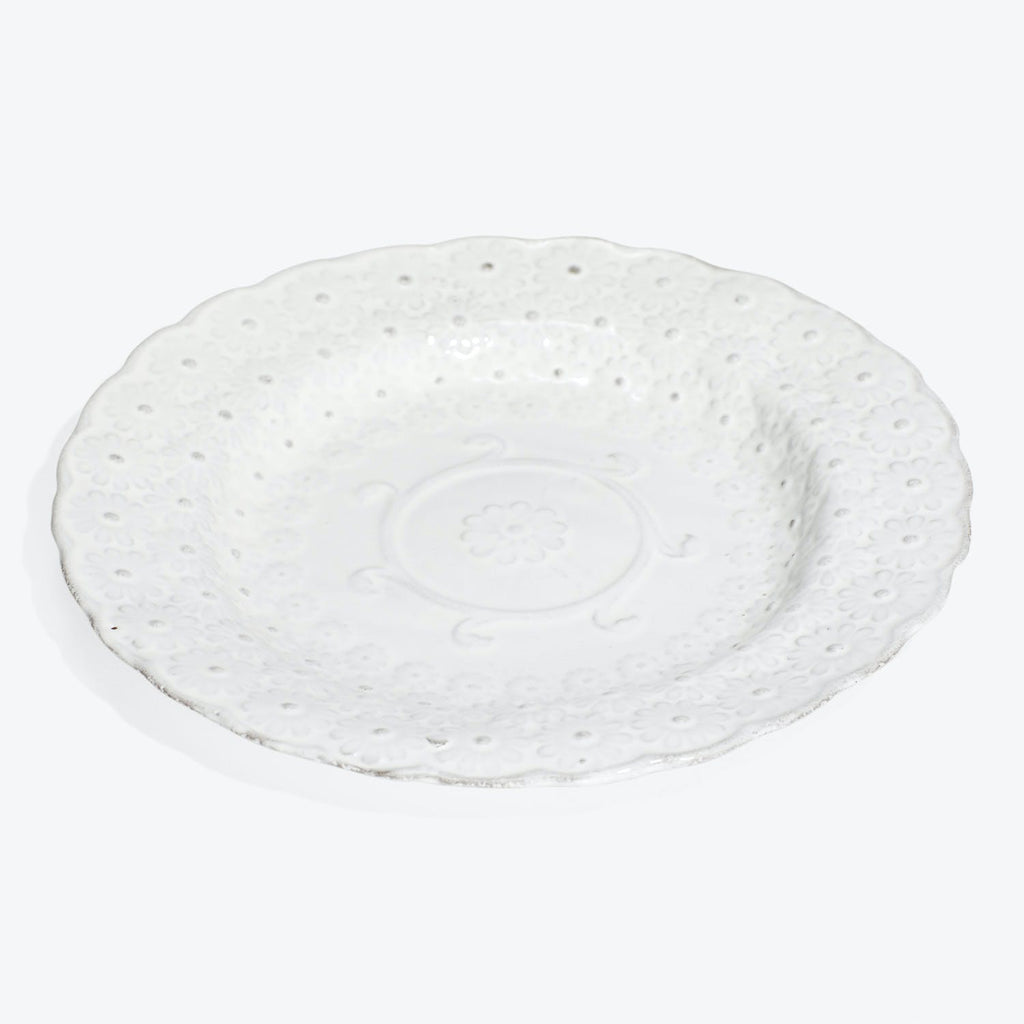 Ornate white ceramic plate with embossed floral design and scalloped edge