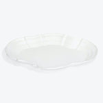 White ceramic plate with scalloped edges, resembling a flower petal.