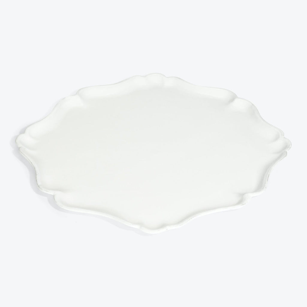 White ceramic plate with scalloped edge and wavy appearance.