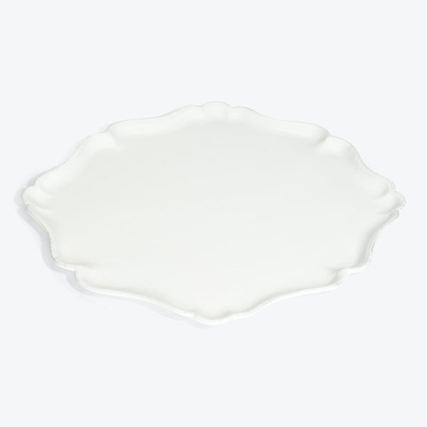 White ceramic plate with scalloped edge and wavy appearance.
