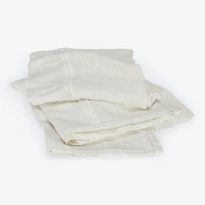 Stack of folded ivory cloths made of thin, semi-translucent fabric.