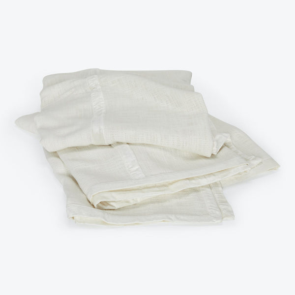 Stack of folded ivory cloths made of thin, semi-translucent fabric.