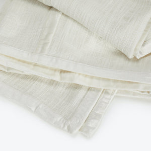 Stack of folded ivory cloths made of thin, semi-translucent fabric. - hover