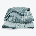Folded plush teal blanket with quilted details and velvety texture.