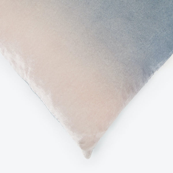 Close-up of a plush cushion with a gradient pink-blue design.