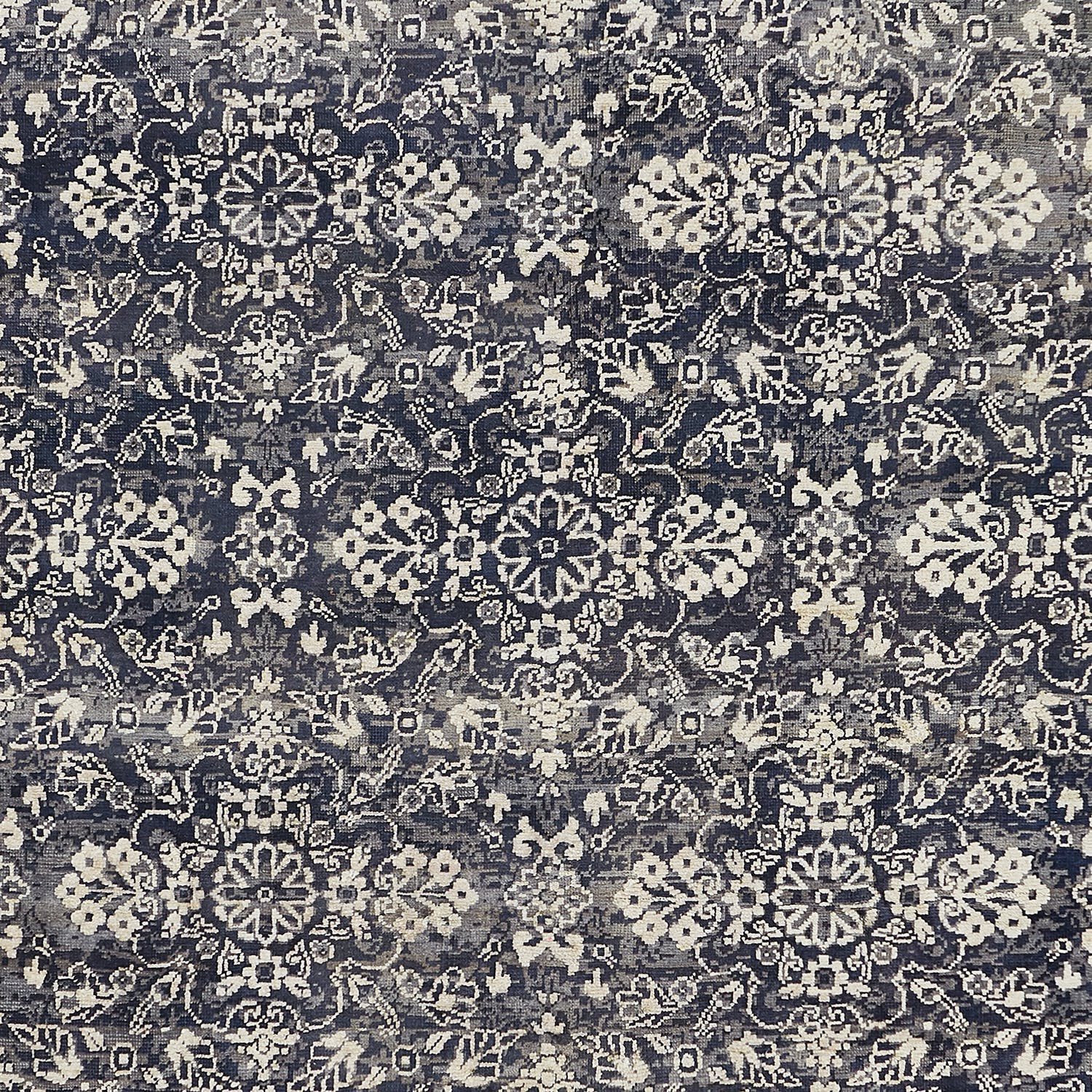 Intricately designed carpet with floral and geometric motifs in monochromatic tones.