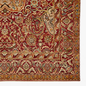 Intricate handwoven Persian-style carpet features rich red background and elaborate botanical pattern.