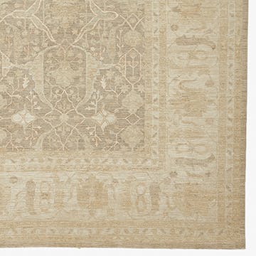 Subtle, faded rug with intricate arabesque motifs in muted tones.