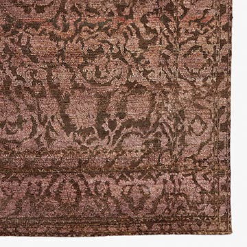 Close-up of a floral damask patterned carpet in brown tones.