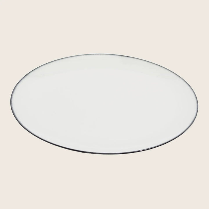 Minimalist white plate with black rim set against white background.