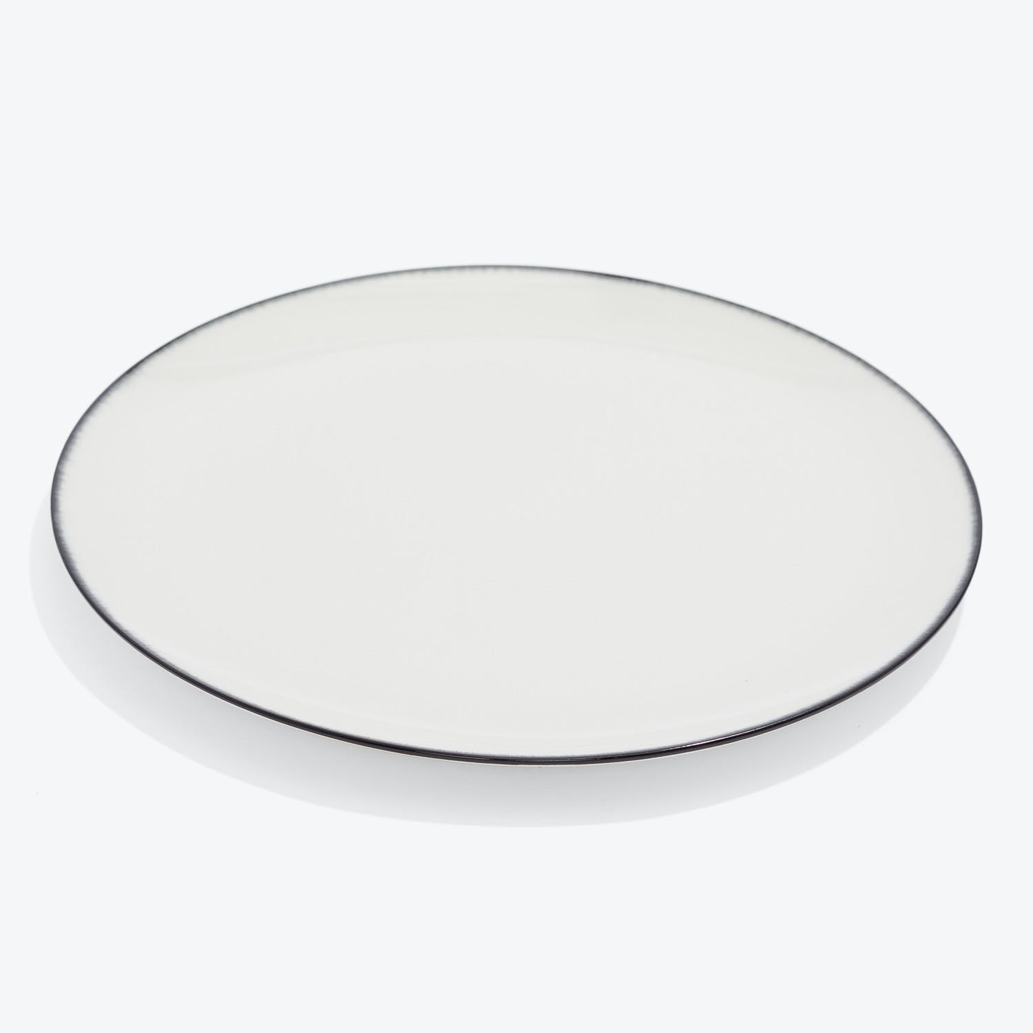 Minimalist white plate with black rim set against white background.