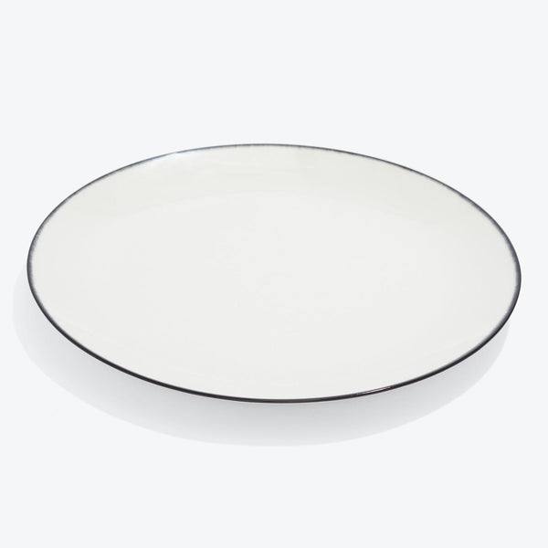 Round white plate with a thin black rim and glossy finish.
