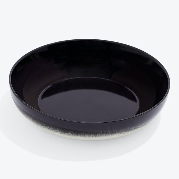 Simple and glossy black bowl reflects light with modern elegance.