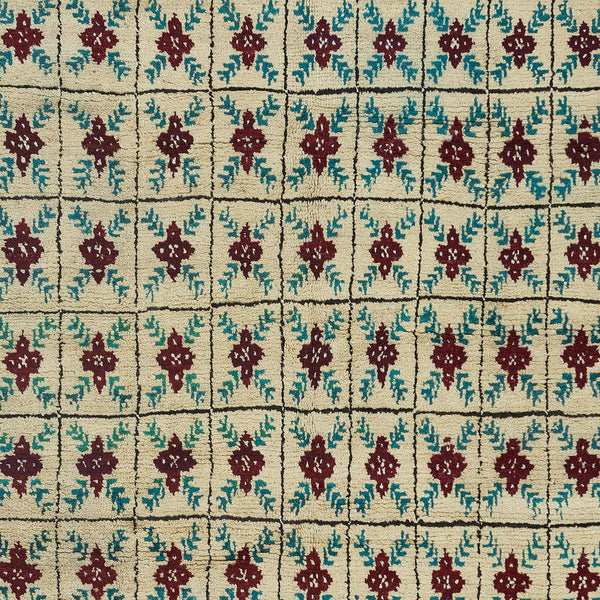 Close-up of a cream, dark red, and teal patterned carpet.