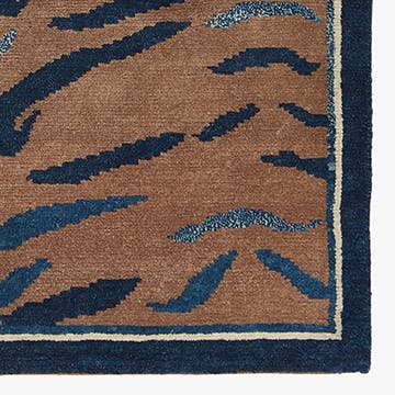 Close-up of a brown rug with abstract blue wave pattern.