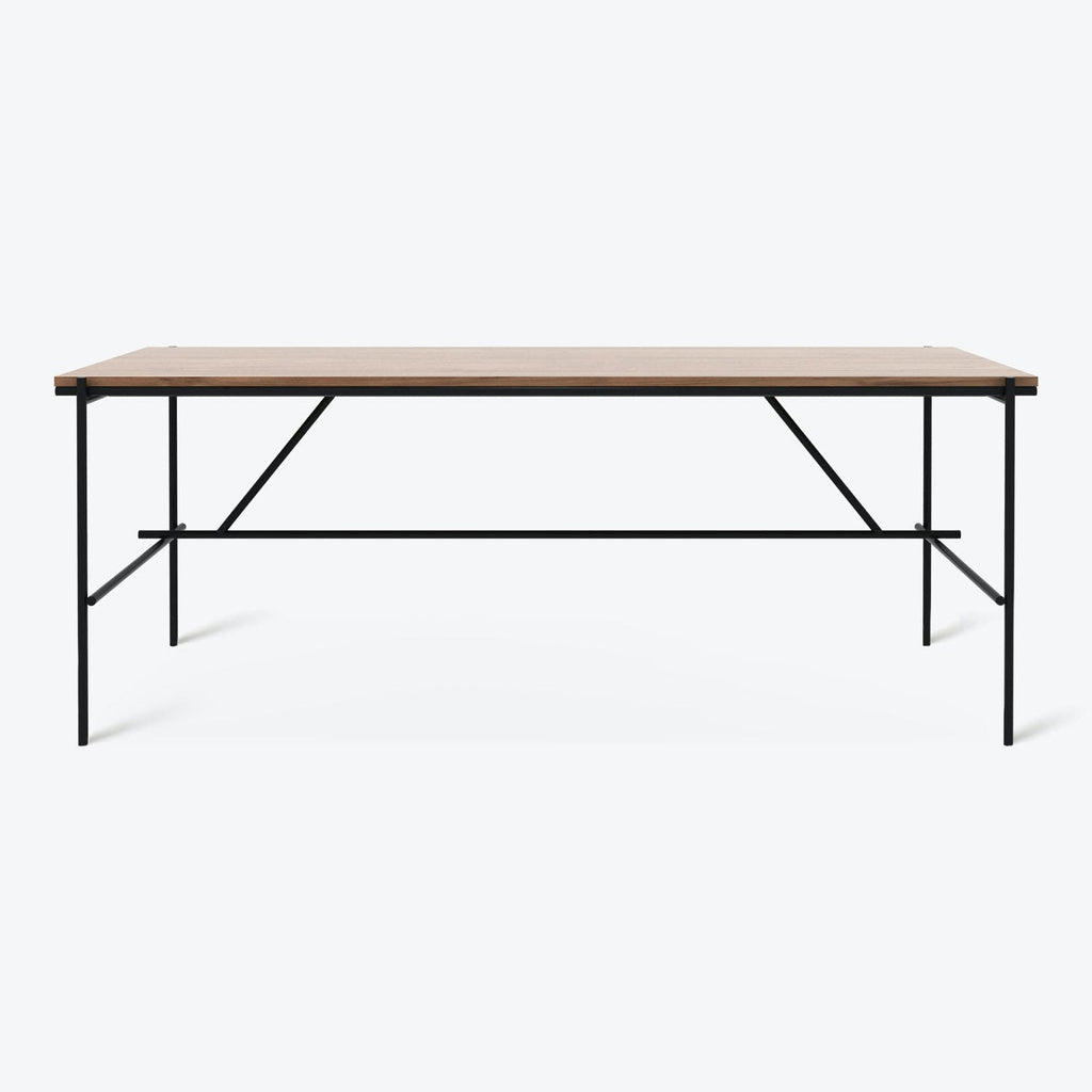 Modern and sleek rectangular table with light wood top and black metal frame and legs.