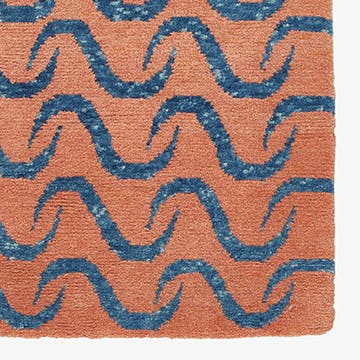 Close-up of a textile with blue wavy lines on terracotta background.