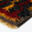 Close-up of tufted fabric with flame-like pattern, matted fibers visible.