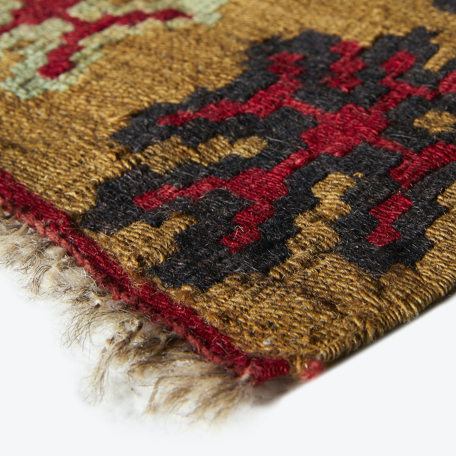 Close-up of a colorful, textured textile with geometric patterns and fringed edges.