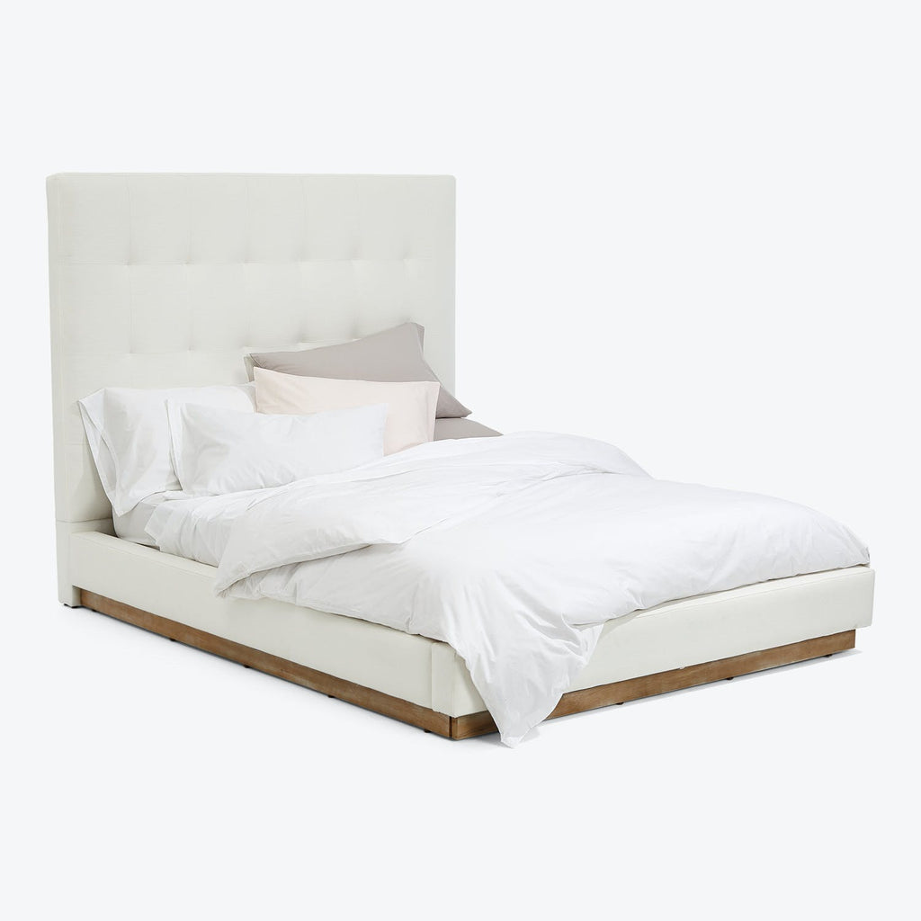 Modern styled bed with tufted headboard and contrasting wooden detail.