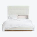 Neatly made bed with white upholstered headboard and tufted design.