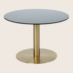 Contemporary round table with black top and golden pedestal stand.